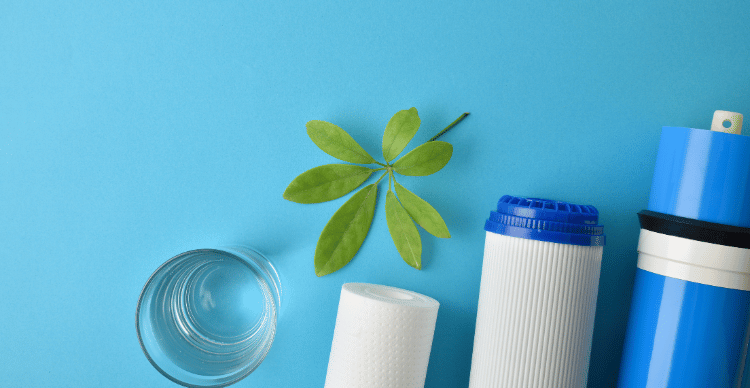 Various types of bacterial filters next to a glass and a green leaf on a blue background.