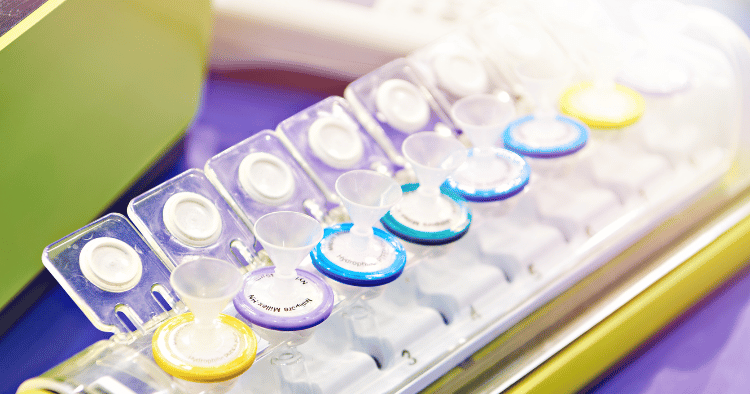 Syringe filters in various colors arranged in a lab setting.