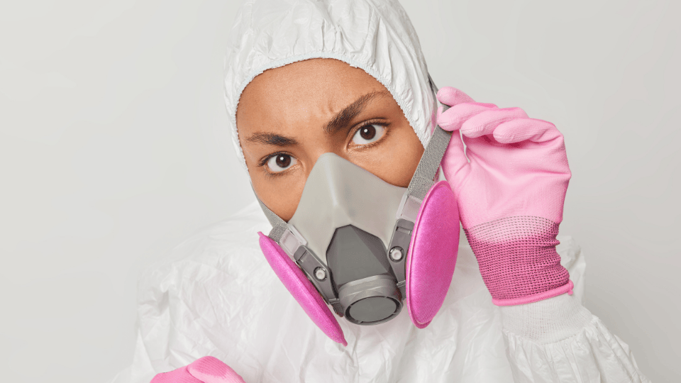 Close-up of a person in a GVS respirator with pink filters, adjusting the mask.